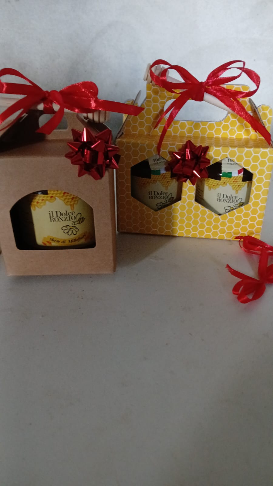 Confezioni regalo natalizie in kraft e a nido d'ape con vasetti Il Dolce Ronzio e fiocchi rossi